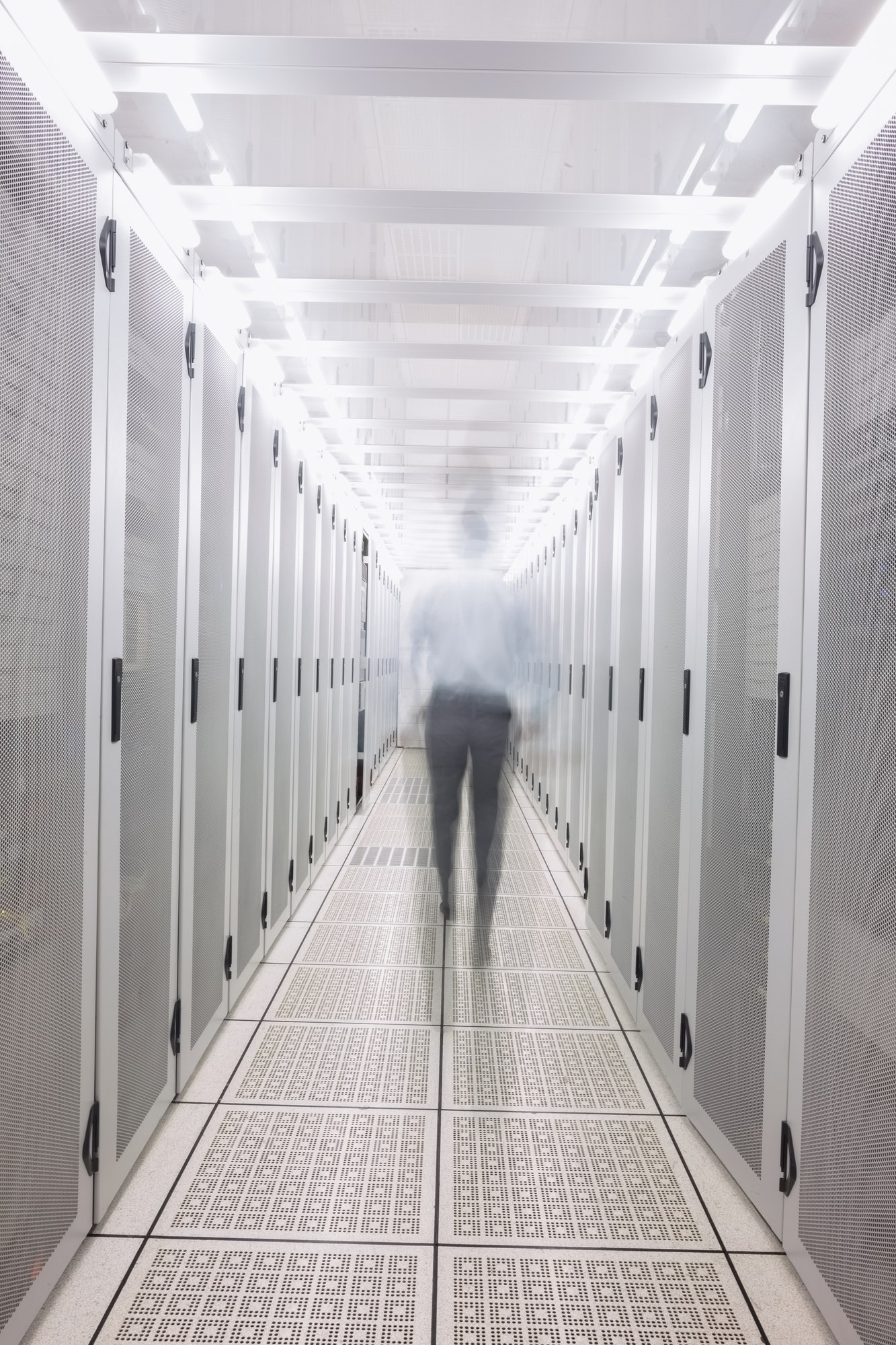Blurred technician walking to the camera in a large data center